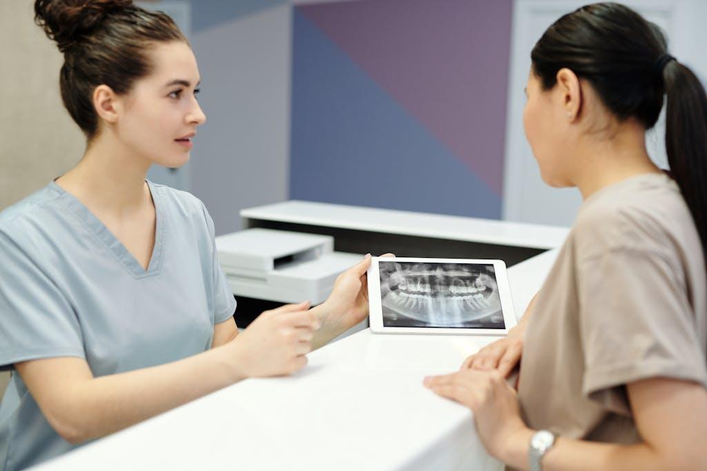 A dentist showing a dental X-ray on a tablet to a patient